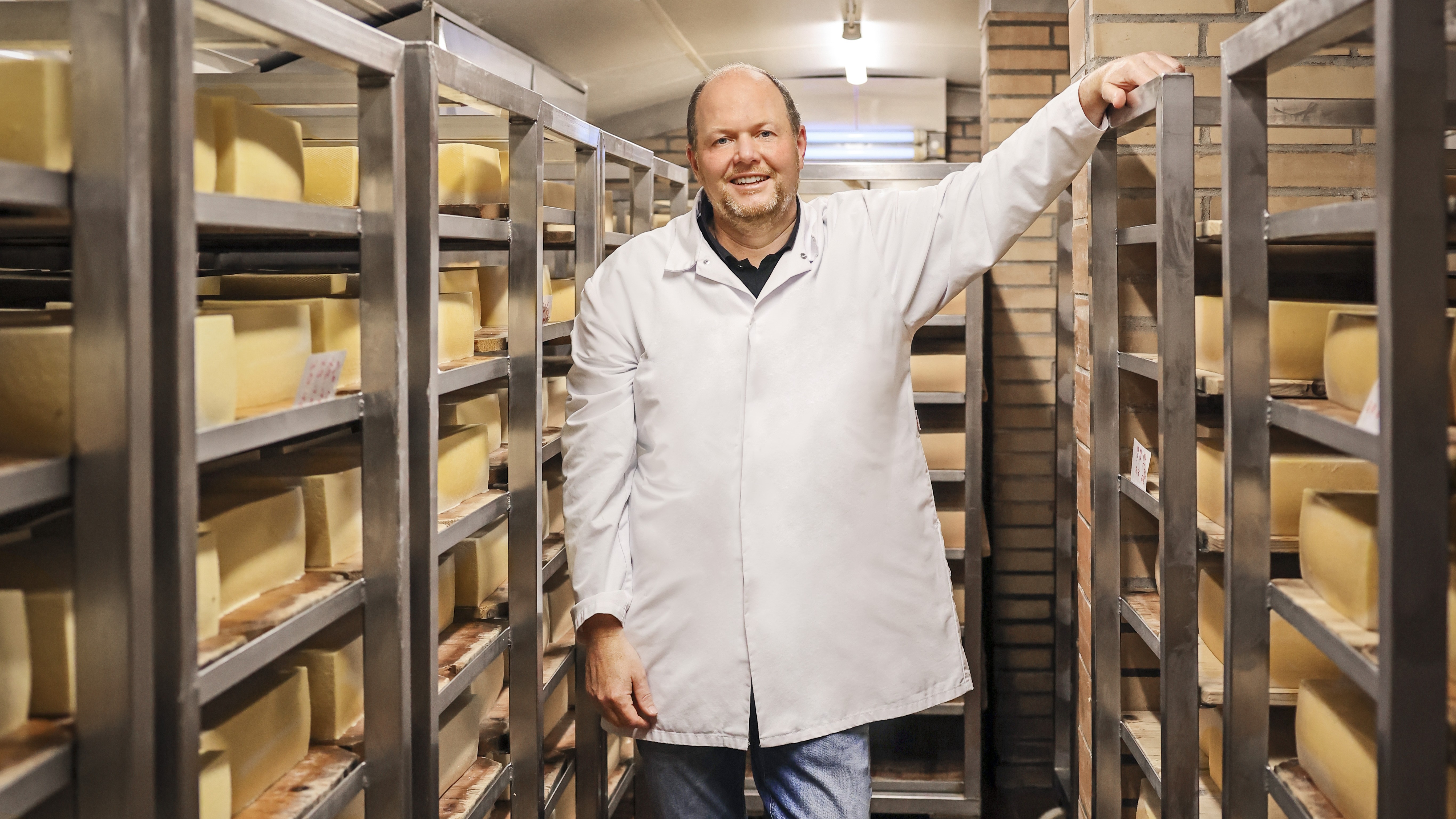 Mann steht in der Käse-Reifekammer