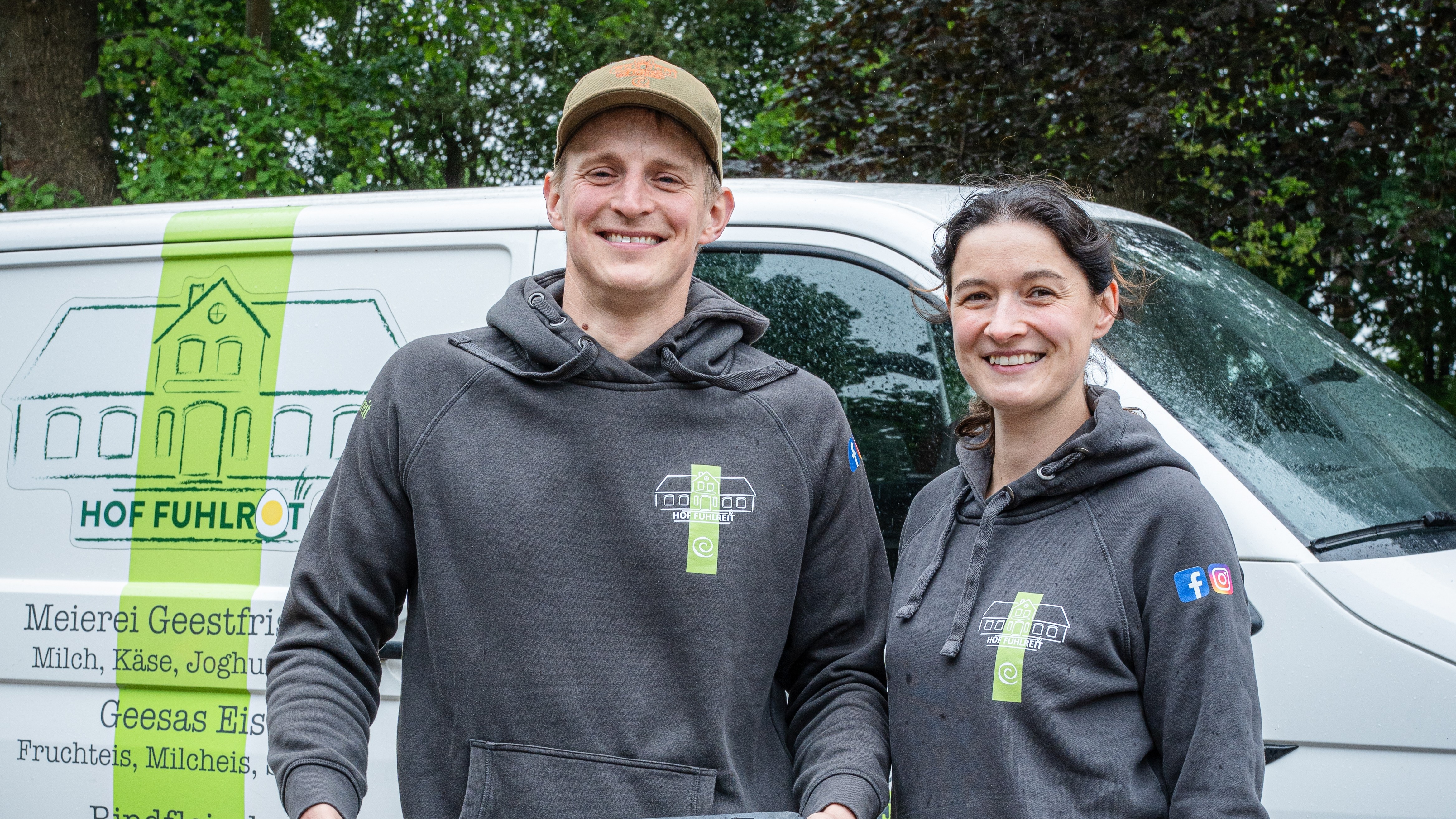 ein Mann und eine Frau stehen vor ihrem Firmenwagen und lächeln in die Kamera