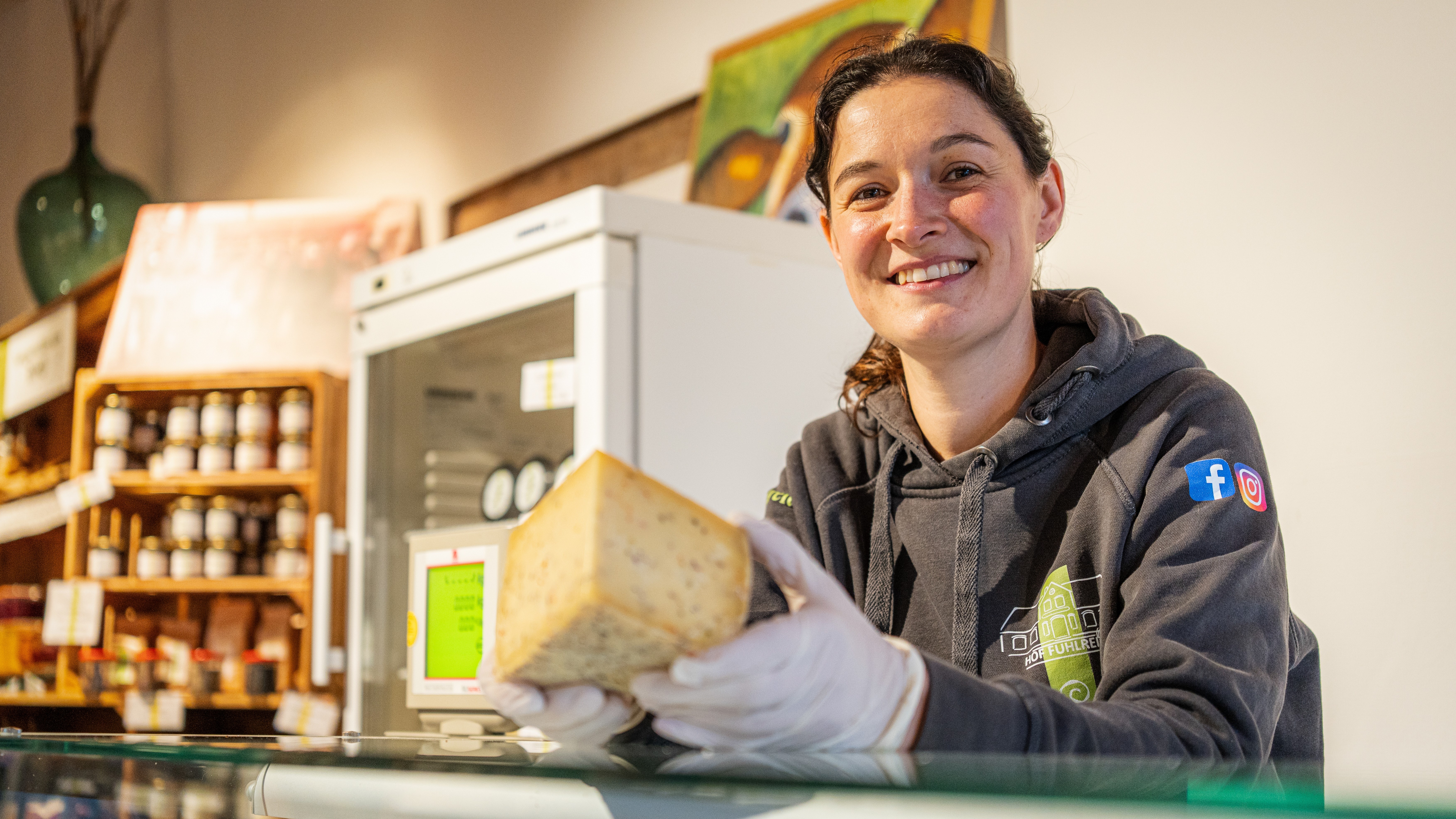 eine Frau präsentiert Käse aus der Käsetheke